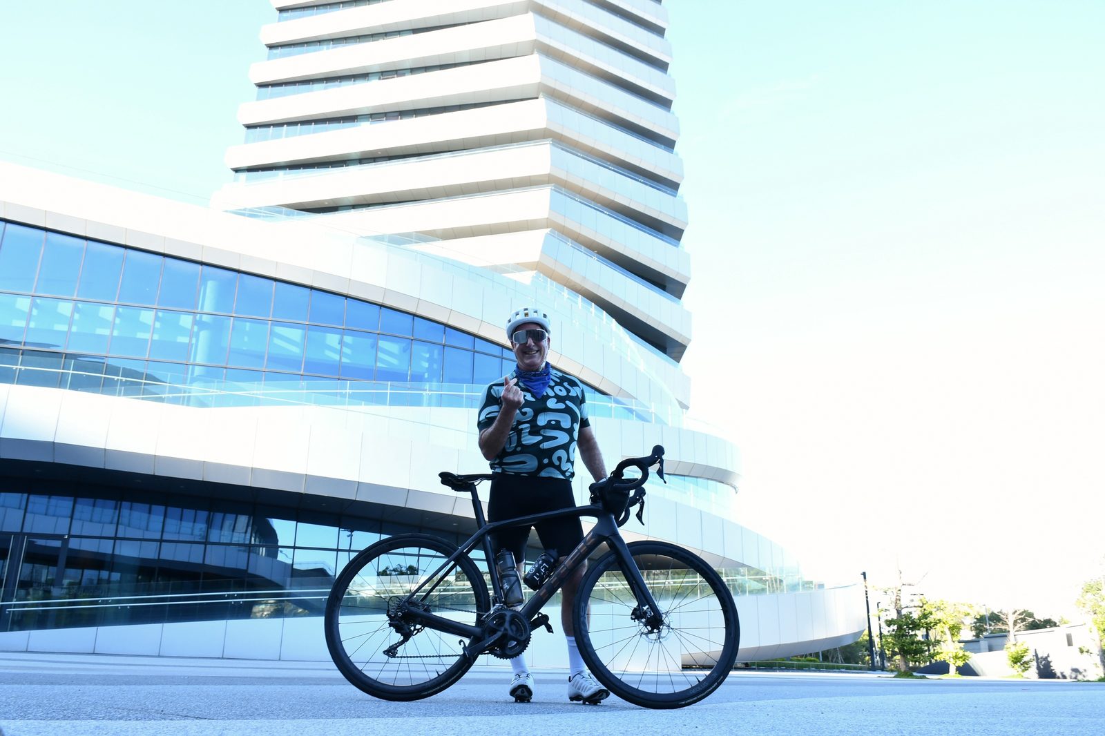 Posing with the bike beneath a modern tower