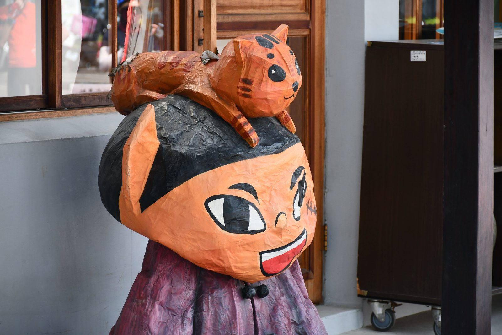 A cat mascot figure with a kitten on its shoulder