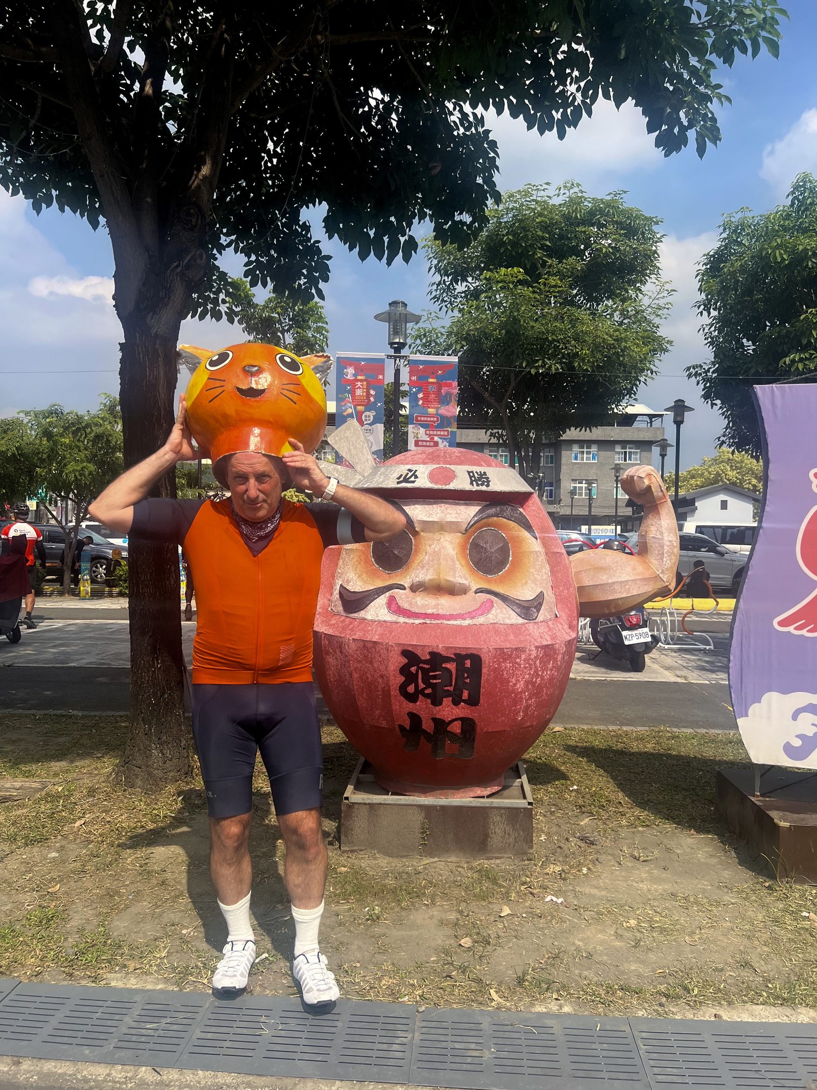 Borrowing a cat mascot head next to the town's daruma statue